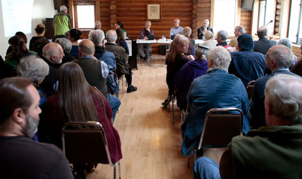 Group of locals in a log building conducting a town hall meeting